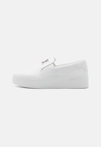 Hvid slip-on sneaker med glat syntetisk materiale, en rundet tå, elastiske sidepaneler og en tyk gummisål. Logoaccent på overdelen.