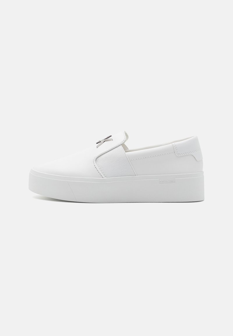 Hvid slip-on sneaker med glat syntetisk materiale, en rundet tå, elastiske sidepaneler og en tyk gummisål. Logoaccent på overdelen.