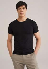 T-shirt noir à manches courtes au design ajusté, fabriqué à partir d'un tissu doux. L'encolure ras du cou et le style minimaliste offrent un look polyvalent.