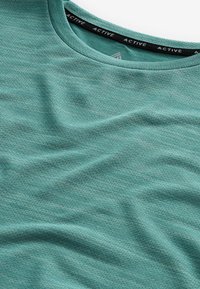 T-shirt de sport texturé vert avec col rond et bande de col intérieure noire étiquetée "ACTIVE".