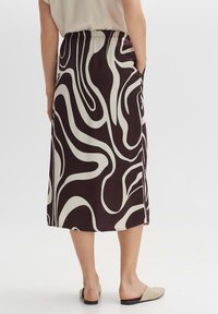 Gonna midi fluida in marrone scuro con motivo astratto bianco a onde, dotata di vita elastica e tasche laterali, realizzata in tessuto leggero.