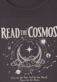 T-shirt grigio scuro con grafica a tema cosmico bianca e testo "LEGGI il COSMO," lune, stelle, pianeti ed elementi decorativi.