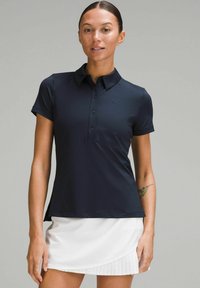 Mornarsko plava polo majica s dugmadi na prednjem dijelu i kratkim rukavima. Ima diskretni logo na prsima i teksturiranu tkaninu.