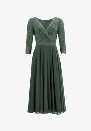 Robe verte avec un corsage en dentelle, des manches trois-quarts et une jupe plissée fluide. Encolure festonnée et détail de fermeture éclair dans le dos.