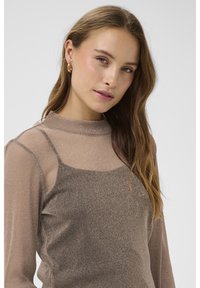 Rudas, blizgantis viršus su aukšta apykakle ir permatomomis rankovėmis. Sluoksniuotas dizainas pasižymi subtilia, tekstūruota rašto.