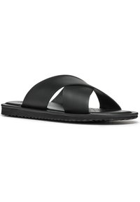 Sandales noires à glissière en matériau synthétique lisse, avec des sangles croisées, une semelle plate et une semelle extérieure texturée pour une meilleure adhérence.