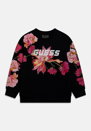 Sweatshirt noir présentant de larges imprimés floraux dans des tons roses et orangés, avec le logo "GUESS" en blanc sur la poitrine. Poignets et ourlet côtelés.