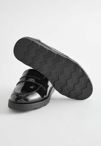Czarne lakierowane buty ze zaokrąglonym noskiem i podwójnym zapięciem. Gruba, teksturowana czarna gumowa podeszwa z wzorem w zygzak.