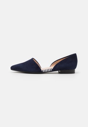Chaussure plate en daim bleu marine avec bout pointu, petit talon et design latéral ouvert montrant la semelle intérieure rayée.