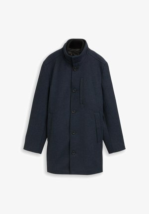 Manteau en laine bleu marine foncé avec un col haute, des boutons devant, des poches latérales et une poche poitrine. Il présente une finition texturée et un design minimaliste.