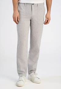 Lichtgrijze gestreepte broek van geweven stof, met rechte pijpen, twee voorzakken en een knoopsluiting aan de voorkant. Gemaakt in combinatie met witte sneakers.