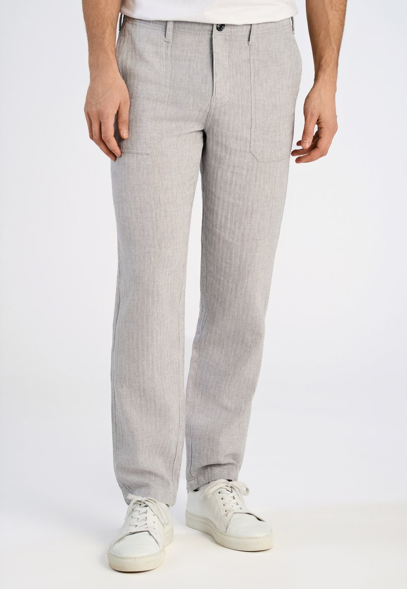 Lichtgrijze gestreepte broek van geweven stof, met rechte pijpen, twee voorzakken en een knoopsluiting aan de voorkant. Gemaakt in combinatie met witte sneakers.