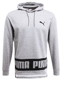 Grå hoodie i mjukt tyg, med en svart logotyp på övre vänster del och fet stil "PUMA"-text på den nedre delen med ett kontrasterande svart band.