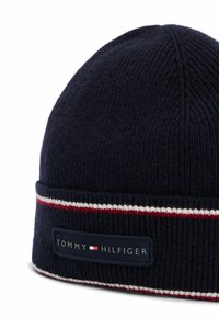 Granatowy dzianinowy czapka z prążkowanym wzorem, z czerwono-białym paskiem i czarną metką z napisem "TOMMY HILFIGER."