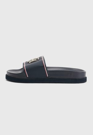 Marineblauwe slideslipper met een gestructureerd voetbed, brede band met rode en witte strepen en een zilveren siergesp.