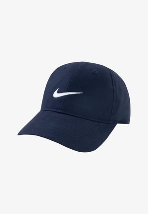 Mornarsko modra kapa iz bombaža, s krovnim vizirjem in belim izvezenim logotipom Nike na sprednji strani. Vključuje prezračevalne luknje.