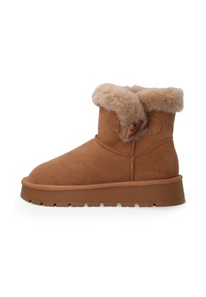 Brown suede ankle boot with thick rubber sole, shearling cuff, and a toggle closure on the side against a white background.