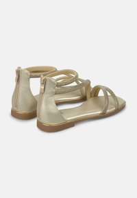 Sandali metallici oro con più cinturini decorati con strass, dotati di una cerniera sul retro e di una suola piatta.