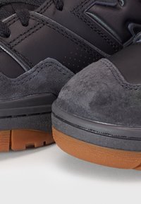 Svarta sportskor med en kombination av läder och mocka. Gummisula i bruna nyanser och vadderade kragar för komfort.