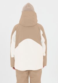 Una giacca beige e bianca con colletto alto e cappuccio, caratterizzata da una texture del tessuto liscia e un blocco di colore angolare sul retro e sulle maniche.