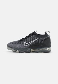 Svart och grå Nike Vapormax Flyknit-sneaker med genomskinlig luftkuddad sula och vitt Nike swoosh-logotyp på sidan.