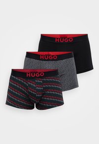 Trei perechi de boxeri din material elastic, cu un design negru, un pattern geometric gri și un pattern colorat cu logo-uri. Toate au talie roșie.