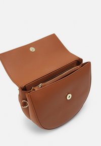 Borsa a tracolla in pelle marrone con forma arrotondata, hardware dorato e un comparto interno con zip. Chiusura a pattina con bottone a pressione.