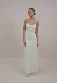 Weißes Maxikleid aus Spitze mit dünnen Trägern und figurbetontem Schnitt, mit einem strukturierten Muster und einer glatten, eleganten Oberfläche.