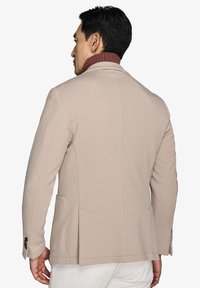Beige blazer med ribbet bordeauxfarvet krave, slim fit, enkelt bagudskær, og sidelommer. Glat tekstur, minimalistisk design.