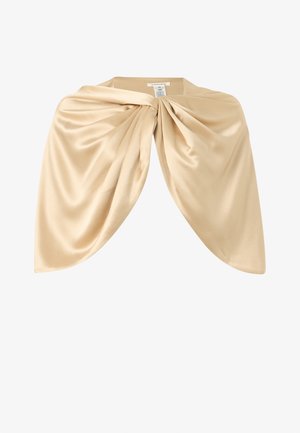 Foulard en satin beige clair drapé et torsadé au centre, montrant une texture de tissu lisse et brillante sur fond blanc.