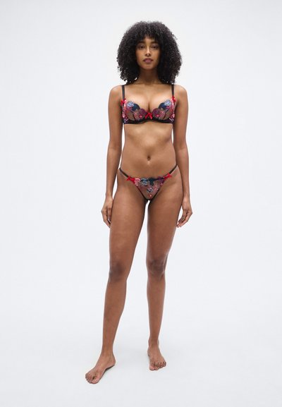 Ensemble soutien-gorge et string en dentelle noire avec broderies florales colorées, accents en nœud rouge, bretelles réglables et détails transparents.