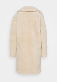Long manteau beige en sherpa avec un large col, montré de dos sur un fond blanc uni.