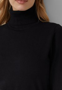 Schwarzer Rollkragenpullover aus weichem Strickmaterial, mit einer enganliegenden Passform und gerippten Akzenten entlang des Halsausschnitts.