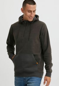 Sudadera de forro polar gris oscuro con collar de media cremallera, cordones ajustables naranjas y bolsillo frontal. Presenta tejido texturizado y puños acanalados.
