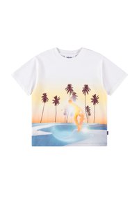 Λευκό μπλουζάκι με skateboarder να εκτελεί ένα κόλπο σε ένα μπλε skate park κατά την ώρα του ηλιοβασιλέματος, με φοίνικες στο φόντο.