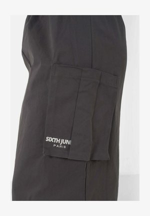 Pantalons cargo noirs en tissu au toucher lisse, dotés d'une poche latérale et d'un logo de marque brodé en blanc sur la poche.
