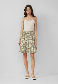 Leichtes Creme-Top mit Spitzenbesatz, kombiniert mit einem kniefreien Rock im grünen Blumenmuster, der einen elastischen Bund und einen gerüschten Saum hat.