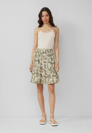 Débardeur léger en crème avec des bordures en dentelle, associé à une jupe longueur genou à motif floral vert, dotée d'une taille élastique et d'un ourlet froncé.