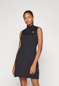 Μαύρο αμάνικο φόρεμα με ψηλό λαιμό, φτιαγμένο από μαλακό υλικό. Διαθέτει ένα μικρό λευκό λογότυπο στη αριστερή πλευρά και έχει χαλαρή, ίσια εφαρμογή.