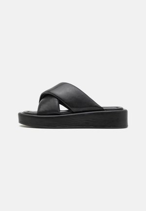 Black platform sandals with crossed straps. Made of smooth leather, featuring a rounded toe and a cushioned footbed for comfort.
