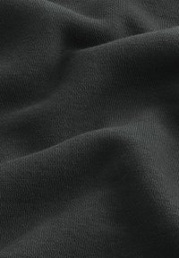 Tessuto nero lavorato a maglia con una texture morbida, caratterizzato da una trama liscia ed uniforme e un leggero lucido. Il materiale presenta pieghe e curve delicate.