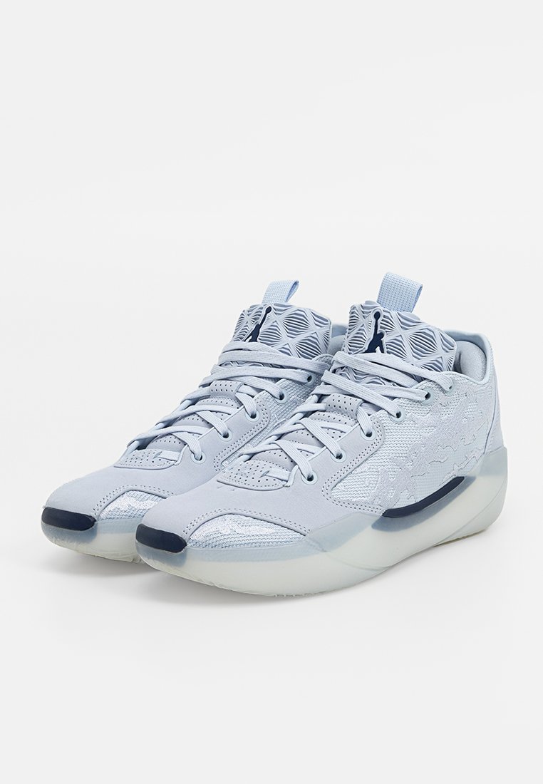 Une paire de baskets montantes bleu clair avec des motifs géométriques, des accents noirs et des semelles épaisses translucides, inclinées vers la droite sur un fond blanc.
