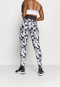 Mustat ja valkoiset kuviolliset leggingsit korkealla vyötäröllä, valmistettu joustavasta kankaasta, jossa on rohkea abstrakti kuvio.