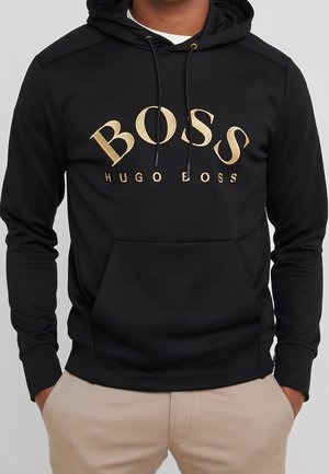 Sudadera negra hecha de una tela suave, con un logo dorado "BOSS" en un diseño en relieve. Incluye cordones y un bolsillo canguro.