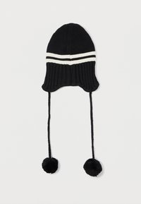 Bonnet en tricot noir avec une texture côtelée, featuring deux rayures blanches horizontales, de longues cordes tressées et des pompons noirs aux extrémités.