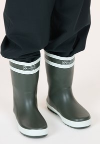 Bottes de pluie en caoutchouc vert avec une bande blanche en haut, présentant une semelle texturée et le logo « ZIGZAG » à l'avant. Surface lisse.