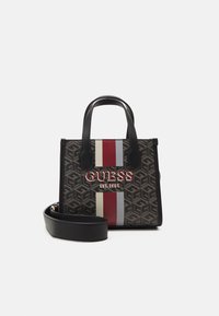 Mustat kuviolliset käsilaukut, joissa on valkoinen ja punainen raita, joissa on näkyvä "GUESS"-logo. Mukana lyhyet kahvat ja irrotettava olkahihna.
