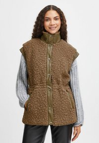 Vest din fâșie sintetică maro cu un guler și un panou frontal matlasat de culoare verde măslin. Prezentă butoane tip snap și buzunare laterale.