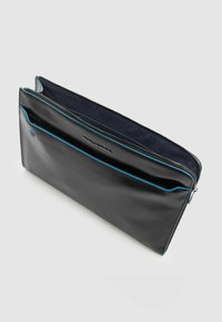 Funda para portátil de cuero negro con un ribete azul, cierre de cremallera y un bolsillo externo. El interior presenta un diseño acolchado para protección.