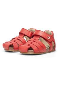 Sandali in pelle rossa con design open-toe, cinturini incrociati e chiusure regolabili in velcro. Fodera interna liscia con suola marrone.